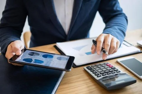 Businessman hands using text information on digital tablet to analyze financi Stock Photos
