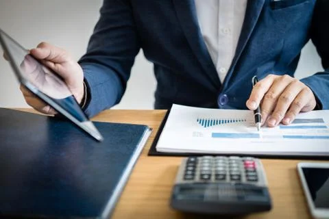 Businessman hands using text information on digital tablet to analyze financi Stock Photos