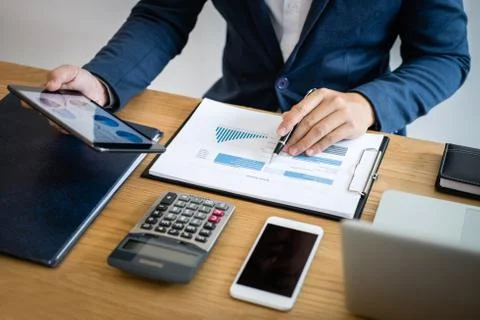 Businessman hands using text information on digital tablet to analyze financi Stock Photos