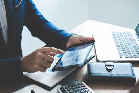 Businessman hands using text information on digital tablet to analyze financi Stock Photos
