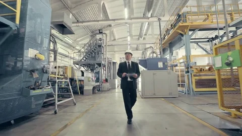 Businessman in hard hat walking through factory Stock Footage 74897592