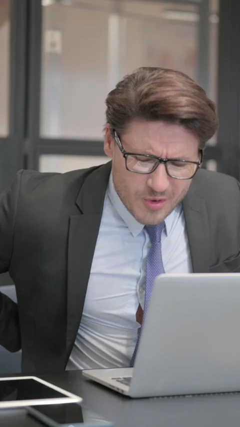 Businessman having Back Pain while Using Laptop in Office, vertical Видео 321118520