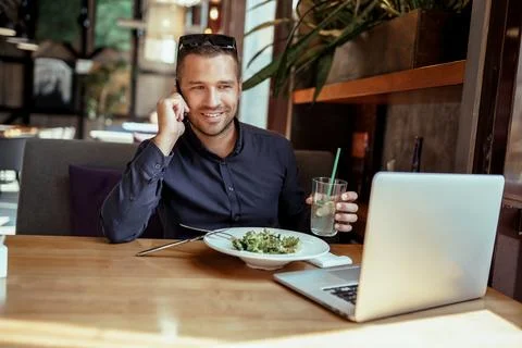 Businessman is having lunch while talking on phone in restaurant. remote work. Stock Photos