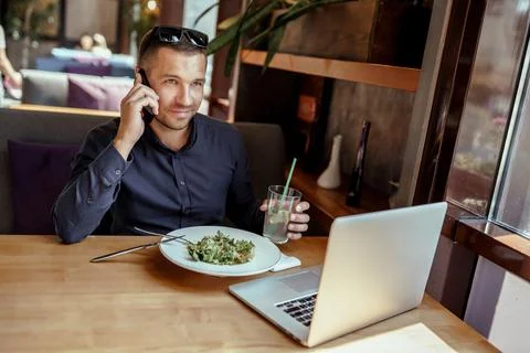 Businessman is having lunch while talking on phone in restaurant. remote work. Stock Photos