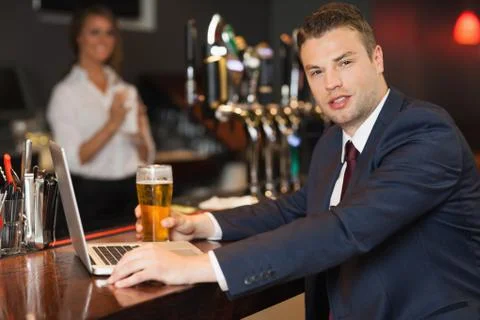 Businessman having a pint while working on his laptop Stock Photos