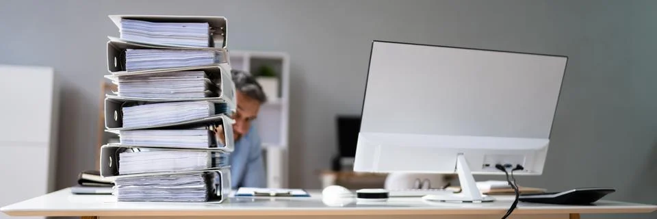 Businessman Hiding Behind The Stack Of Folders On Desk Foto stock