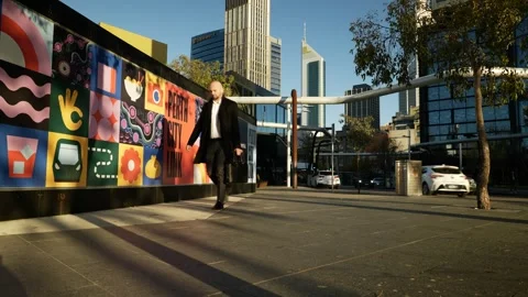 Businessman holding a briefcase passes Perth development billboard 6K Stock Footage 312242453