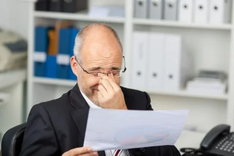 Businessman holding document while rubbing eyes 写真素材