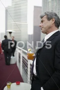 Businessman holding a drink at a roof top bar Stock Photos