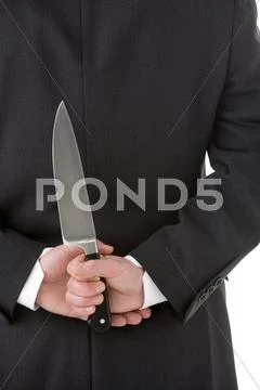 Businessman holding knife behind his back Stock Photos