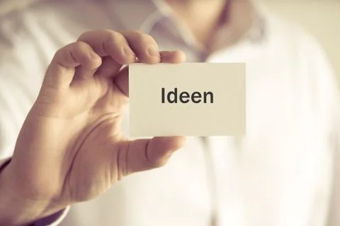 Businessman holding message card "IDEEN" written in German - translation : ID Stock Photos