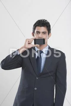 Businessman holding a mobile phone in front of his mouth Stock Photos