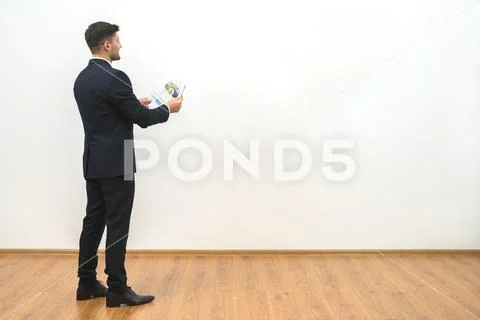 The businessman holding papers on the white wall background Stock Photos