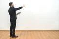 The businessman holding a tablet and gesturing on the white wall background Photo