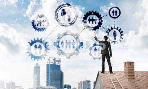 Businessman on house roof presenting teamwork and connection concept. Mixed Stock Photos