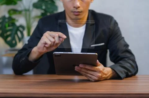 Businessman Interacting with Transparent Digital Interface While Using a Ta.. Stock Photos