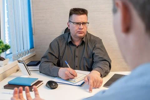 Businessman interviewing a job candidate while taking notes during an office  库存照片