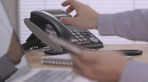 Businessman on laptop in modern office, typing on smartphone answers desk phone Stock Footage