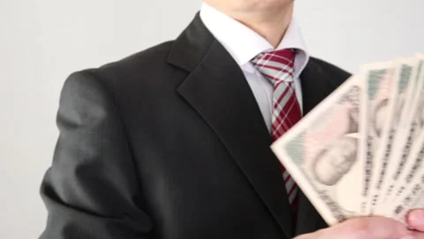 A businessman looking back while holding the new 10,000 yen bill Stock Footage 325688909