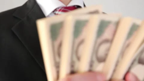 A businessman looking back while holding a wad of bills Stock Footage 325689062