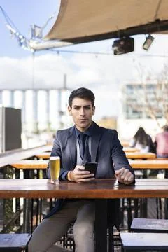Businessman looking at camera e while holding his smartphone Stock Photos