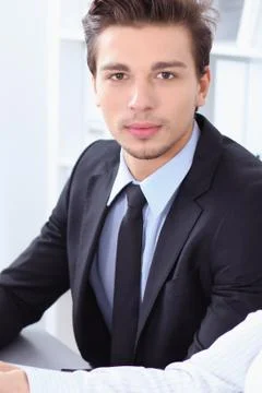 Businessman looking at camera while partners shaking hands at meeting Stockfoto's