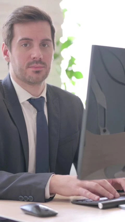 Businessman Looking at Camera while Using Desktop Computer, vertical video Stock Footage 328977491