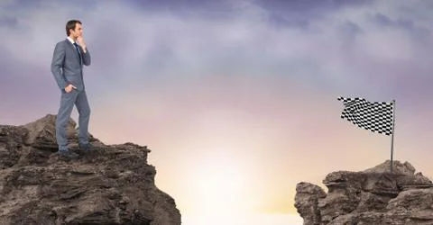 Businessman looking at checkered flag while standing on rocks against sky Stock Photos