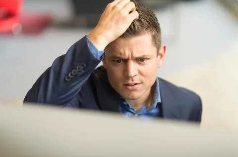 Businessman looking at computer in office scratching his head Stock Photos