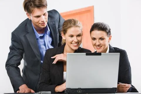 Businessman is looking at computer worked by two colleagues Stockfoto's