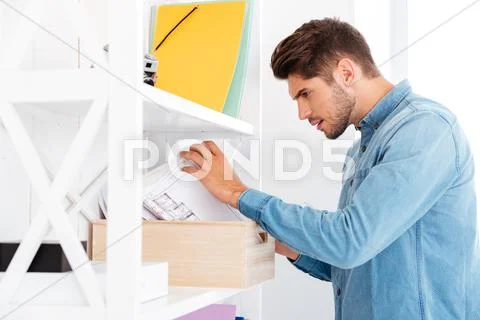 Businessman looking for documents in office shelf Stock Photos
