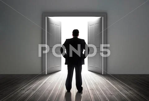 Businessman looking at door showing bright light Stock Photos