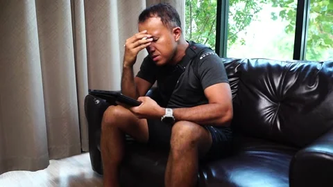 Businessman looking stressed while using a work on tablet Stockbeeldmateriaal 220664307