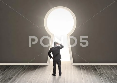 Businessman looking through a keyhole shape door Stock Photos