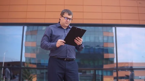 A businessman is looking at working papers while two business girls are walking Stock Footage 94808609