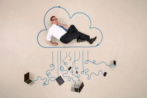 Businessman lying in a cloud connected to mobile devices Fotos Stock