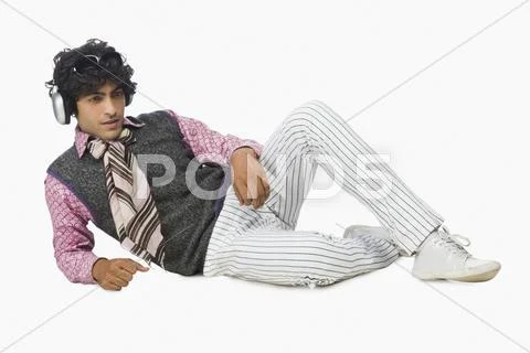 Businessman lying down and listening to headphones Stock Photos