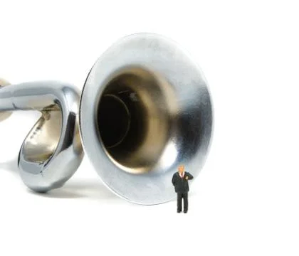 A businessman makes a speech while presenting in front of a large silver horn Stock Photos