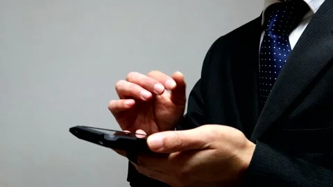 A businessman makes a triumphant gesture while operating his smartphone. Stock Footage 336414218
