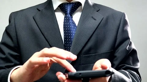 A businessman makes a triumphant gesture while operating his smartphone. Video stock 336415729