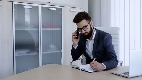 Businessman Making Phone Call While Sitting In Office Video stock 76327672