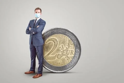 Businessman with a mask standing next to a big 2 Euro coin Stock Photos