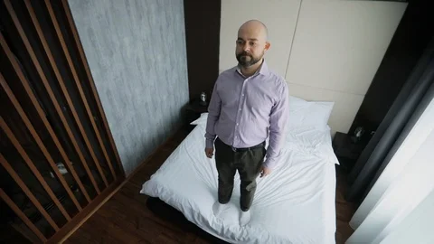 Businessman in office clothes is falling back on the bed in a hotel room. Stock Footage 106087996