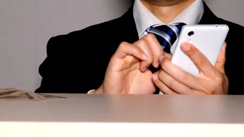 A businessman operating his smartphone while holding banknotes. Stock Footage 334834838