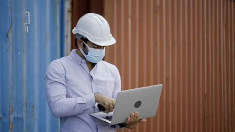 Businessman or engineer wearing hardhat, wearing face mask using laptop Stock Footage 159278504