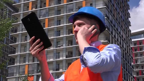 Businessman outdoors construction developer talking to mobile phone using tablet Stock Footage 76045390