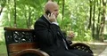 Businessman in Park Sitting on a Bench Talk to Mobile and Eat a Sandwich 4k or 4k+ Resolution