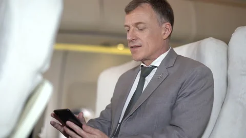 Businessman passengers using smartphone sitting in airplane Stock Footage 167049877