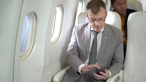 Businessman passengers using smartphone sitting in airplane Stock Footage 167049904