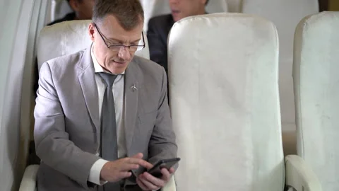 Businessman passengers using smartphone sitting in airplane Stock Footage 167050740